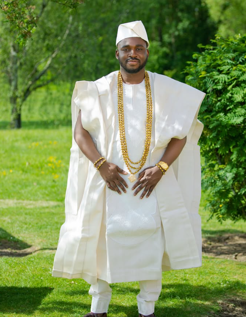 Groom in cream traditional agbada with gold beads photographed in a garden