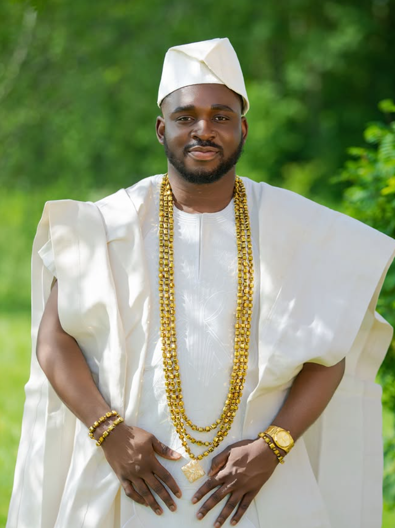 Portrait of a groom in cream agbada and cap wearing layered gold beads