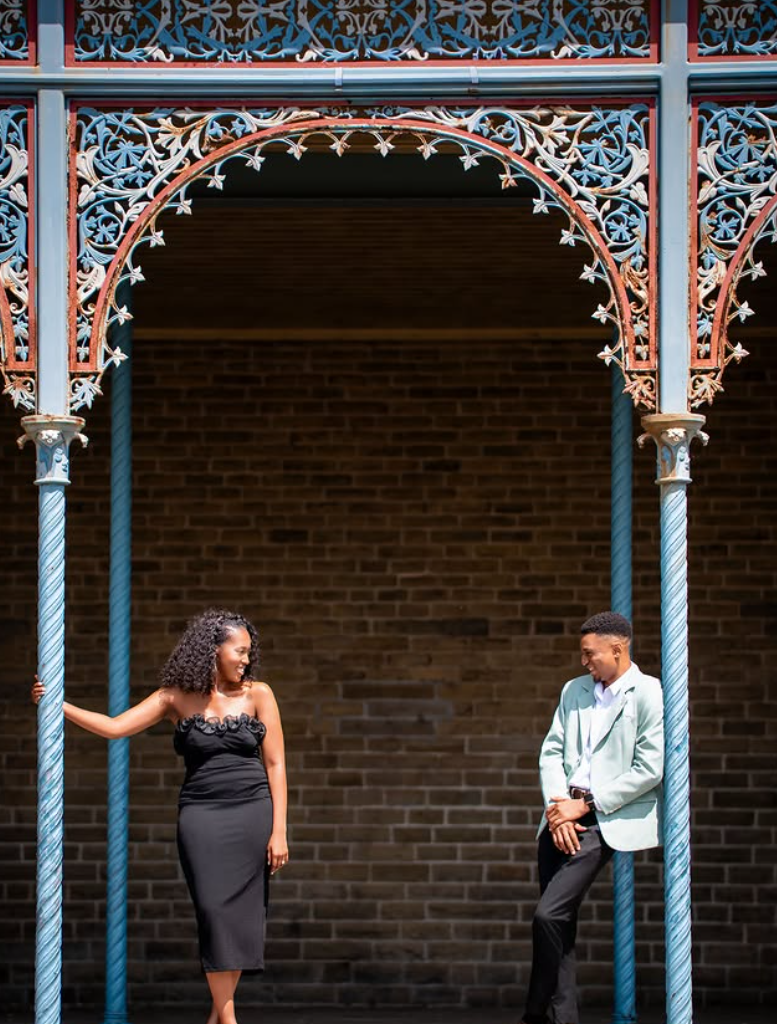Couple photographed either side of an ornate ironwork archway